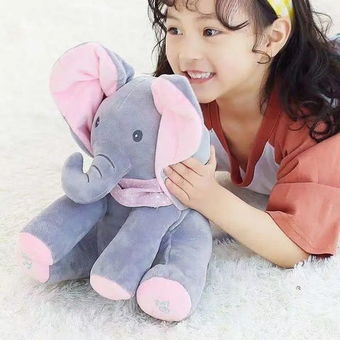 Child holding a plush elephant toy on a soft surface